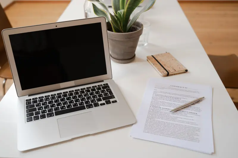 Bureau avec un ordinateur portable, une plante et un document imprimé prêt à être signé