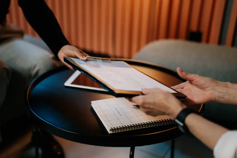 Un CV sur porte-bloc passe d'une main à l'autre au-dessus d'une table basse