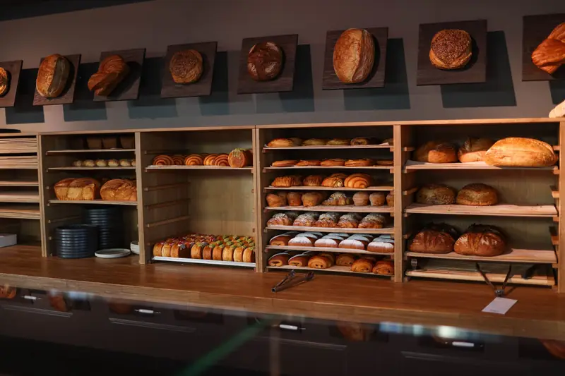 Comptoir de boulangerie aux étagères en bois garnies de pains et de viennoiseries