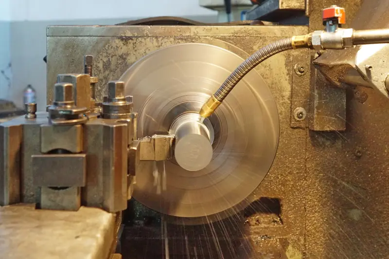Tour à métaux en plein usinage d'une pièce cylindrique en acier, dans un atelier